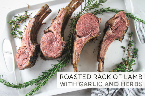 Roasted Lamb on white serving platter with herb garnishes. 