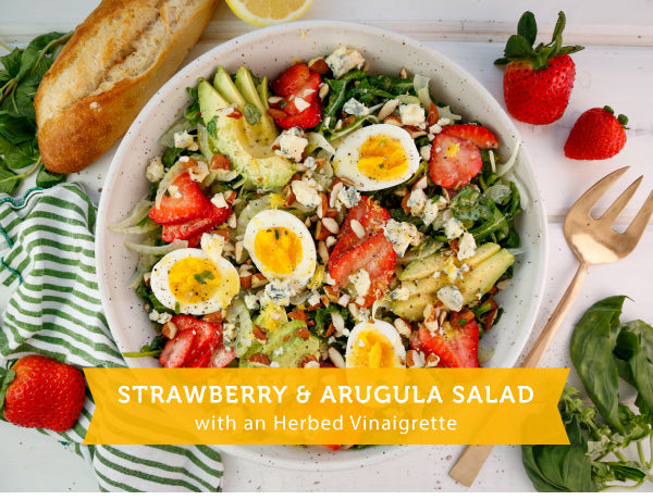 arugula salad topped with strawberries, avocado, and hard boiled eggs